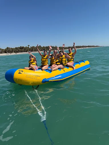 Friends laughing on a yellow banana boat in clear Gulf water